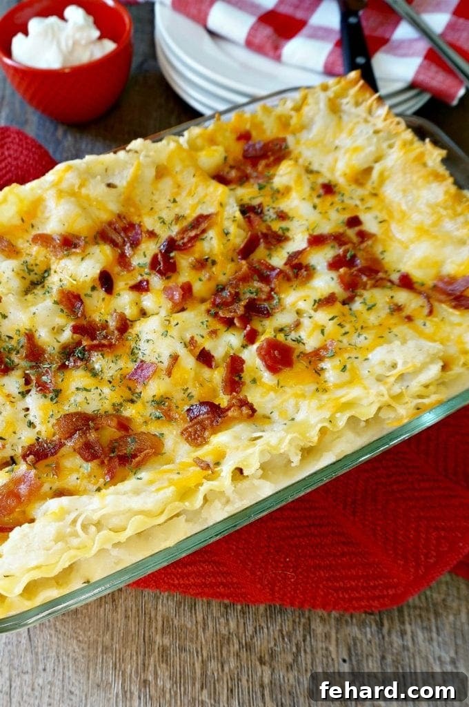A baked Mashed Potato Lasagna in a glass casserole dish, garnished with fresh herbs and crumbled bacon.