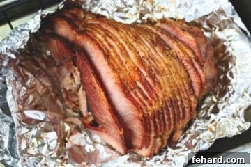 Spiral sliced ham glazed with Dijon Pineapple glaze baked in foil on roasting pan.