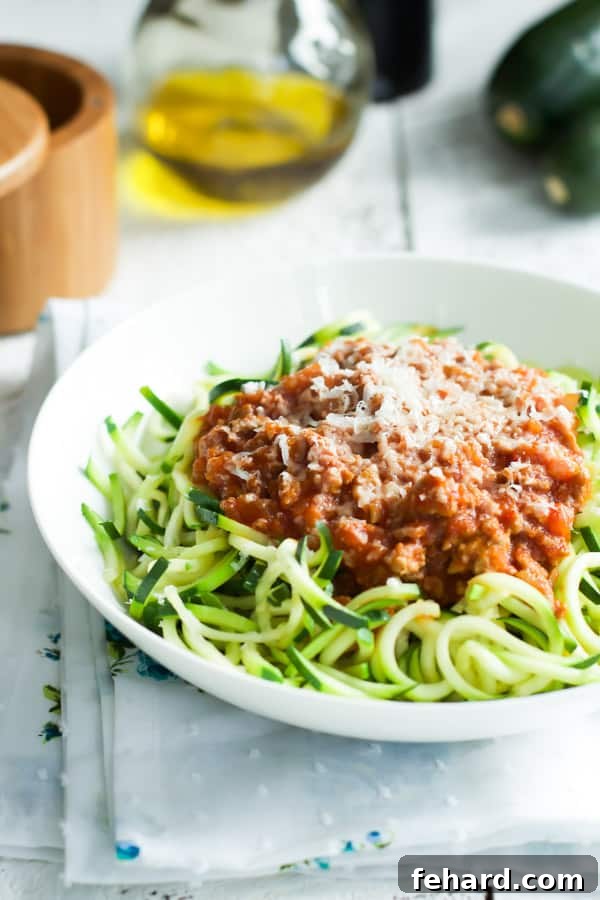 A white bowl filled with Turkey Bolognese Zucchini Pasta, garnished with fresh basil.