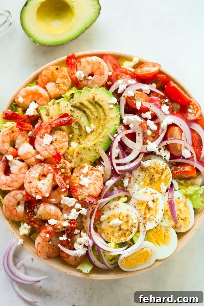 60 Delicious Whole30 Recipes 6 An inviting overhead view of a vibrant shrimp salad, bursting with creamy avocado and ripe tomatoes, presented in a rustic wooden bowl.