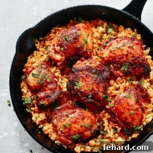Overhead view of a black skillet with spicy chicken and cauliflower rice, a complete meal.