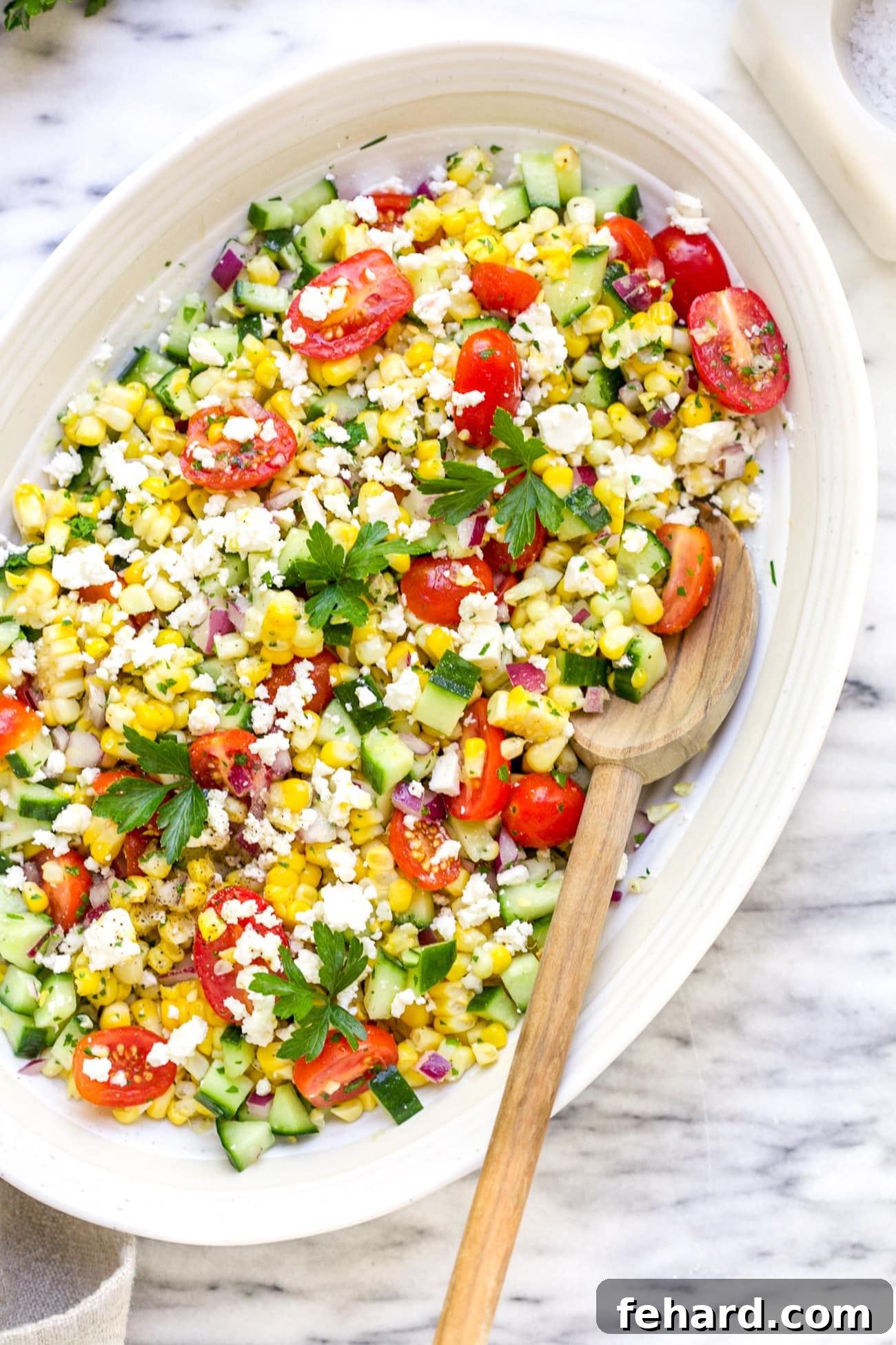 Overhead view of a vibrant corn salad in a white bowl, bursting with fresh summer flavors.