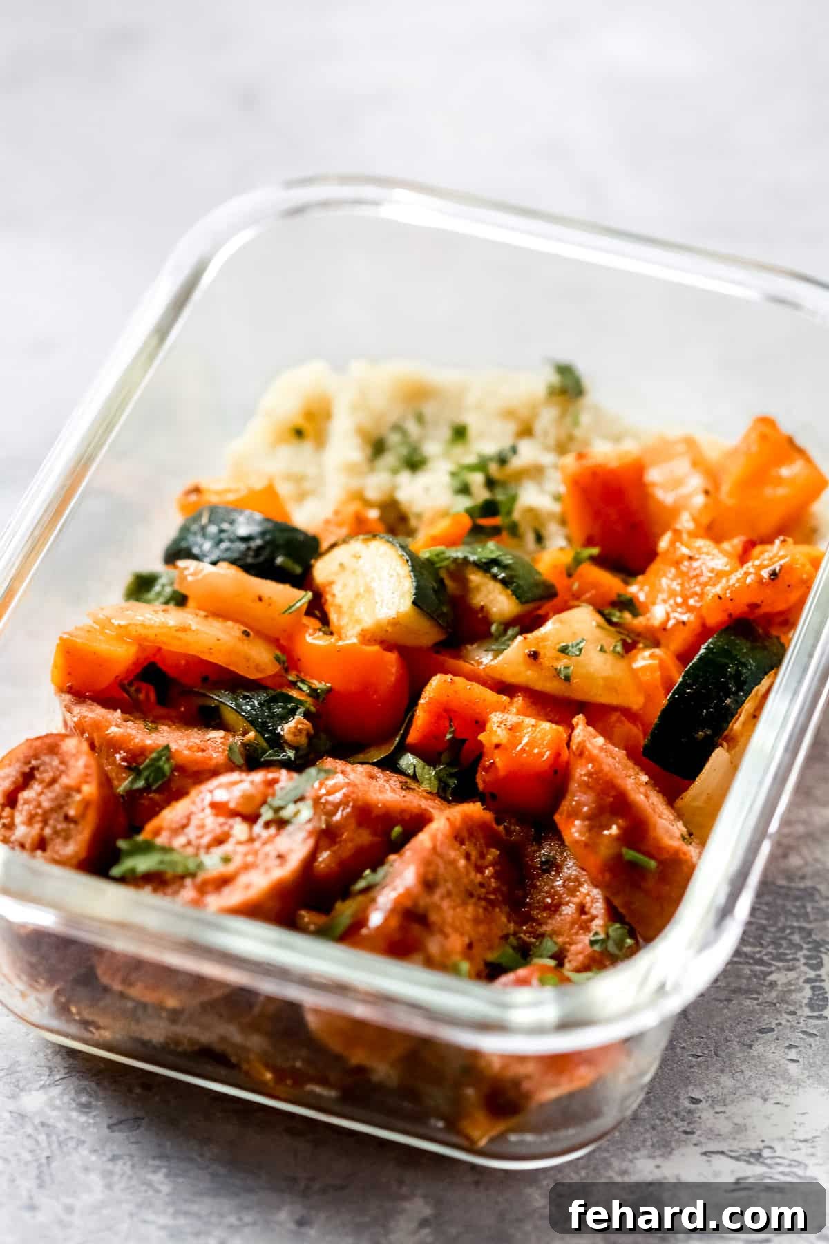close up of a glass meal prep bowl of sausage and veggies