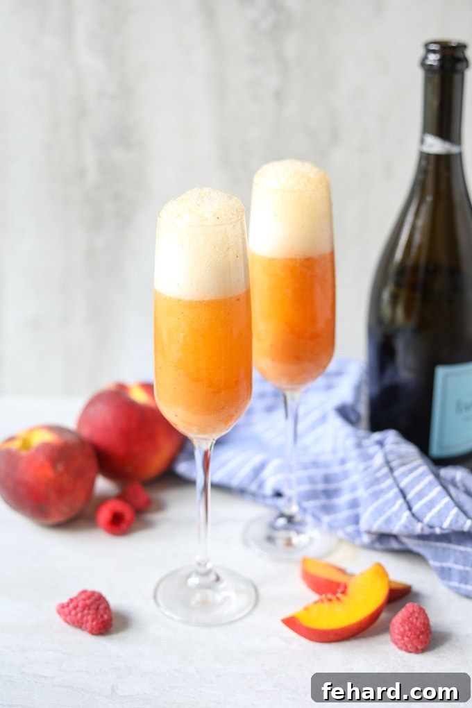 Two Bellini cocktails next to a bottle of Prosecco, highlighting their vibrant peach color and elegant presentation.