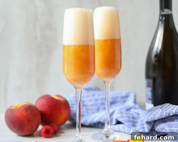 Two beautifully presented peach Bellini cocktails with a bottle of chilled Prosecco in the background, ready for enjoyment.