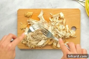 Hearty Instant Pot Chicken Tortilla Soup 7 Showing 2 forks shredded chicken on cutting board.