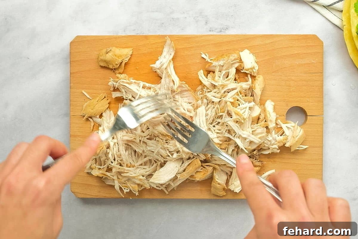 Instapot Tortilla Soup with Chicken Showing 2 forks shredded chicken on cutting board.