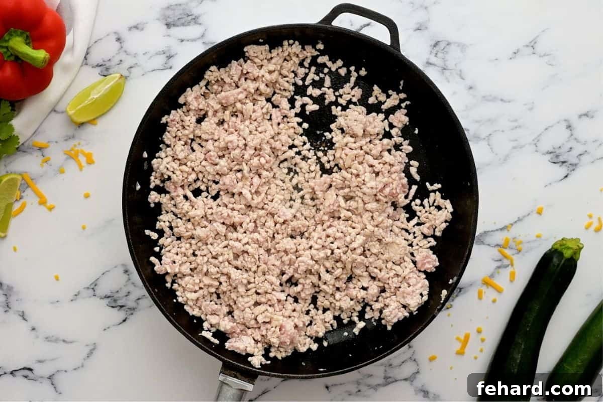 Browning Ground Turkey for Taco Skillet Close-up of lean ground turkey browning in a large skillet, broken into small, uniform pieces.