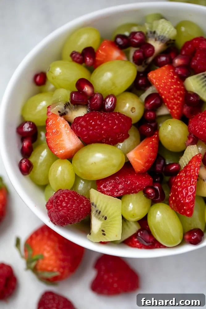 Red and green fruit tossed in a white serving bowl, ready for a Christmas brunch.
