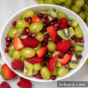 Bowl of red and green fruit salad, glistening with dressing.