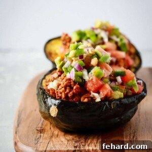 Close up view of taco stuffed acorn squash on a wooden serving board, garnished with fresh cilantro.