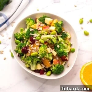 Bowl of healthy broccoli salad next to oranges, emphasizing the fresh, vibrant ingredients and the appealing presentation.