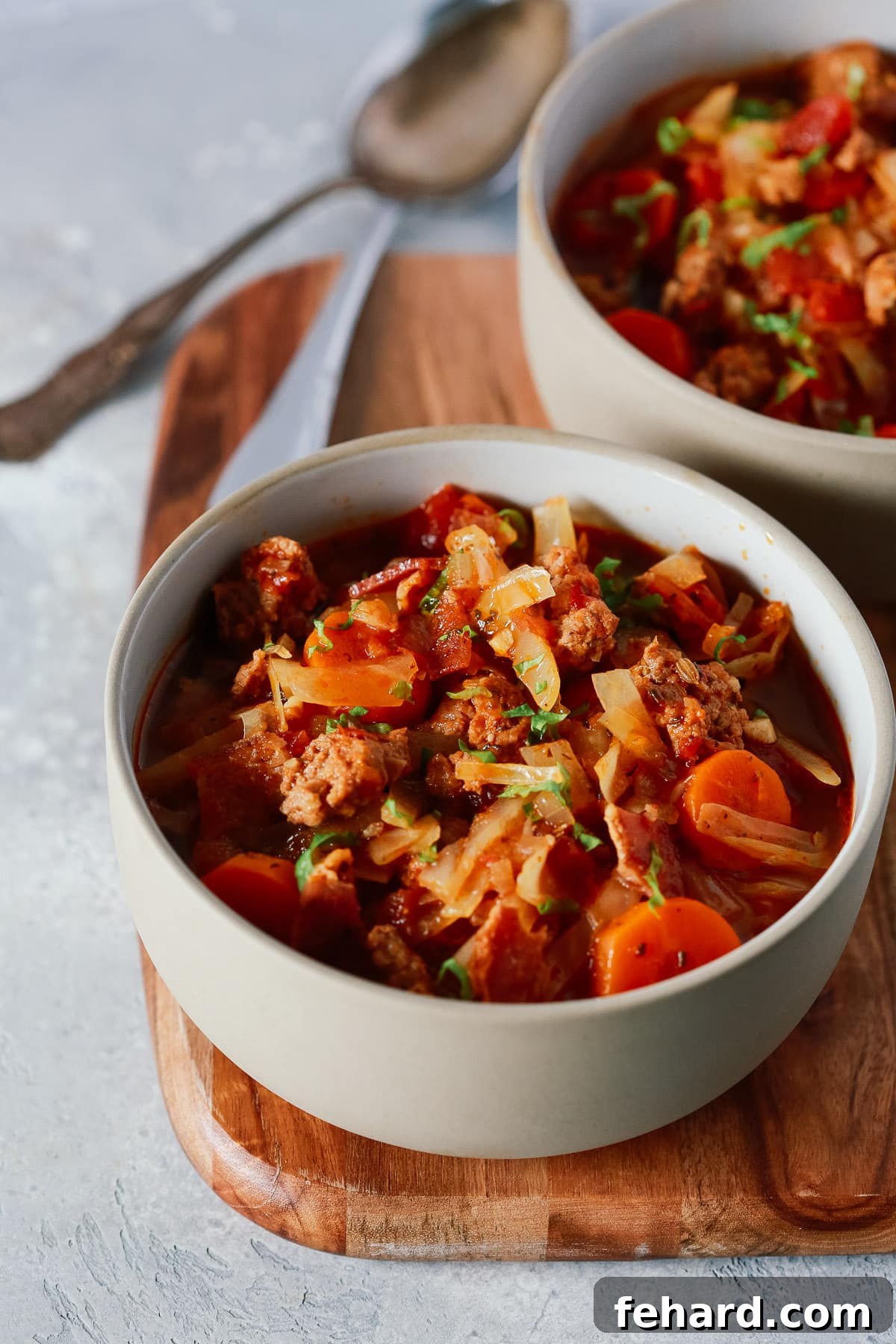 Close-up of a serving of Cabbage and Sausage Stew in a grey bowl, highlighting the texture and rich ingredients.