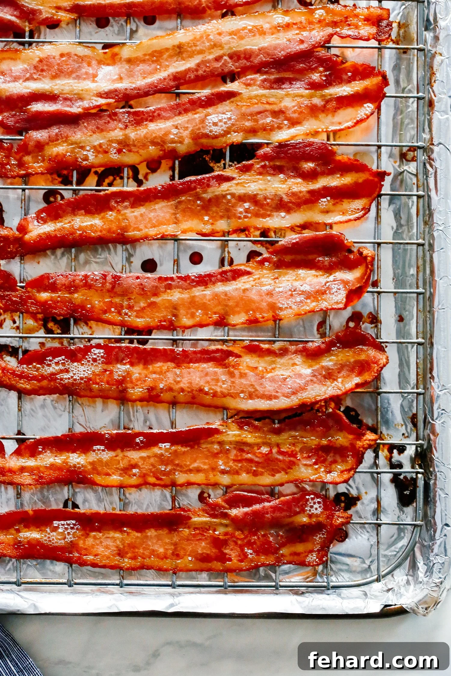 Close-up of crispy cooked bacon on a wire rack atop a foil-lined baking sheet, ready to be enjoyed.