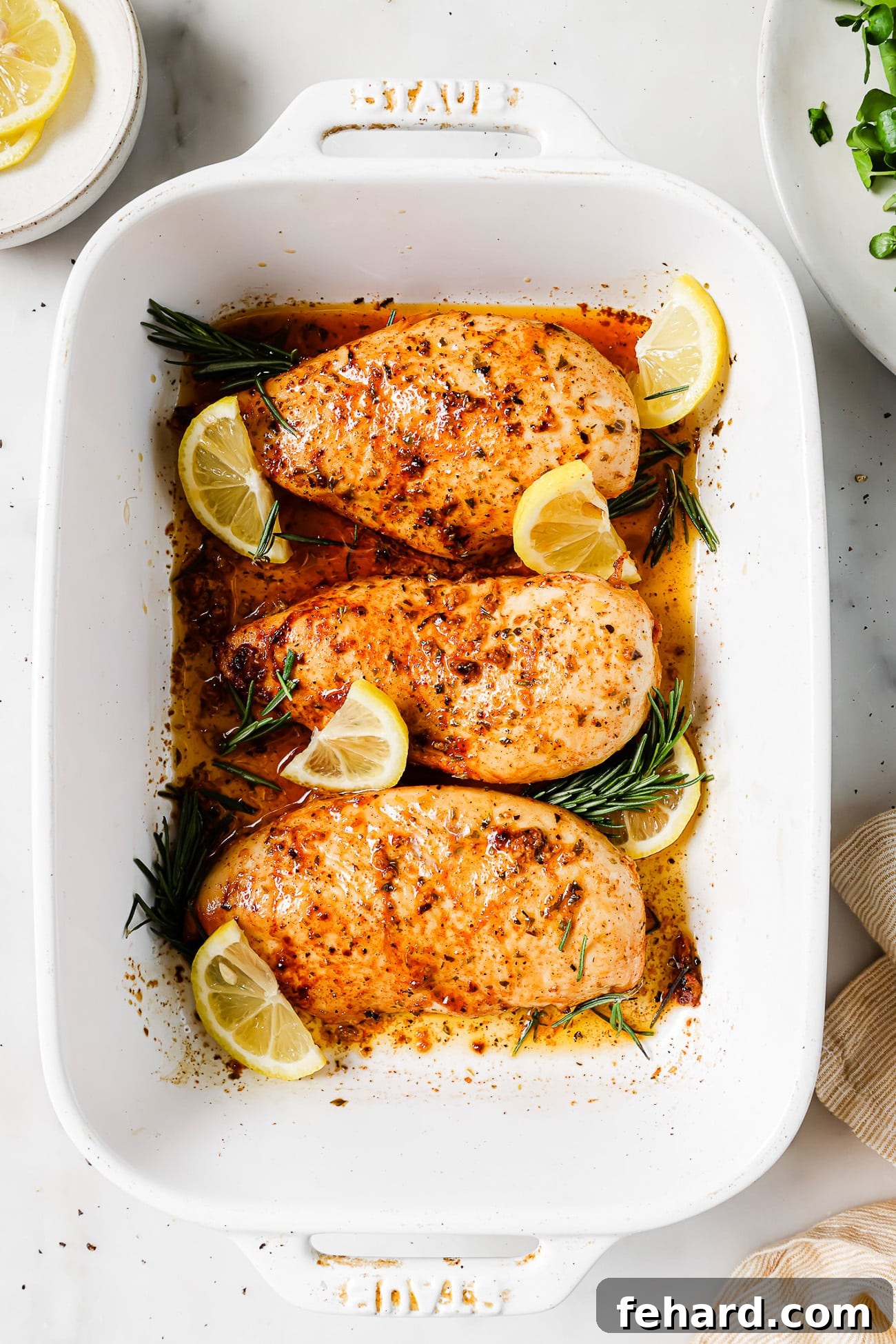 Overhead view of lemon rosemary chicken in a white casserole dish.
