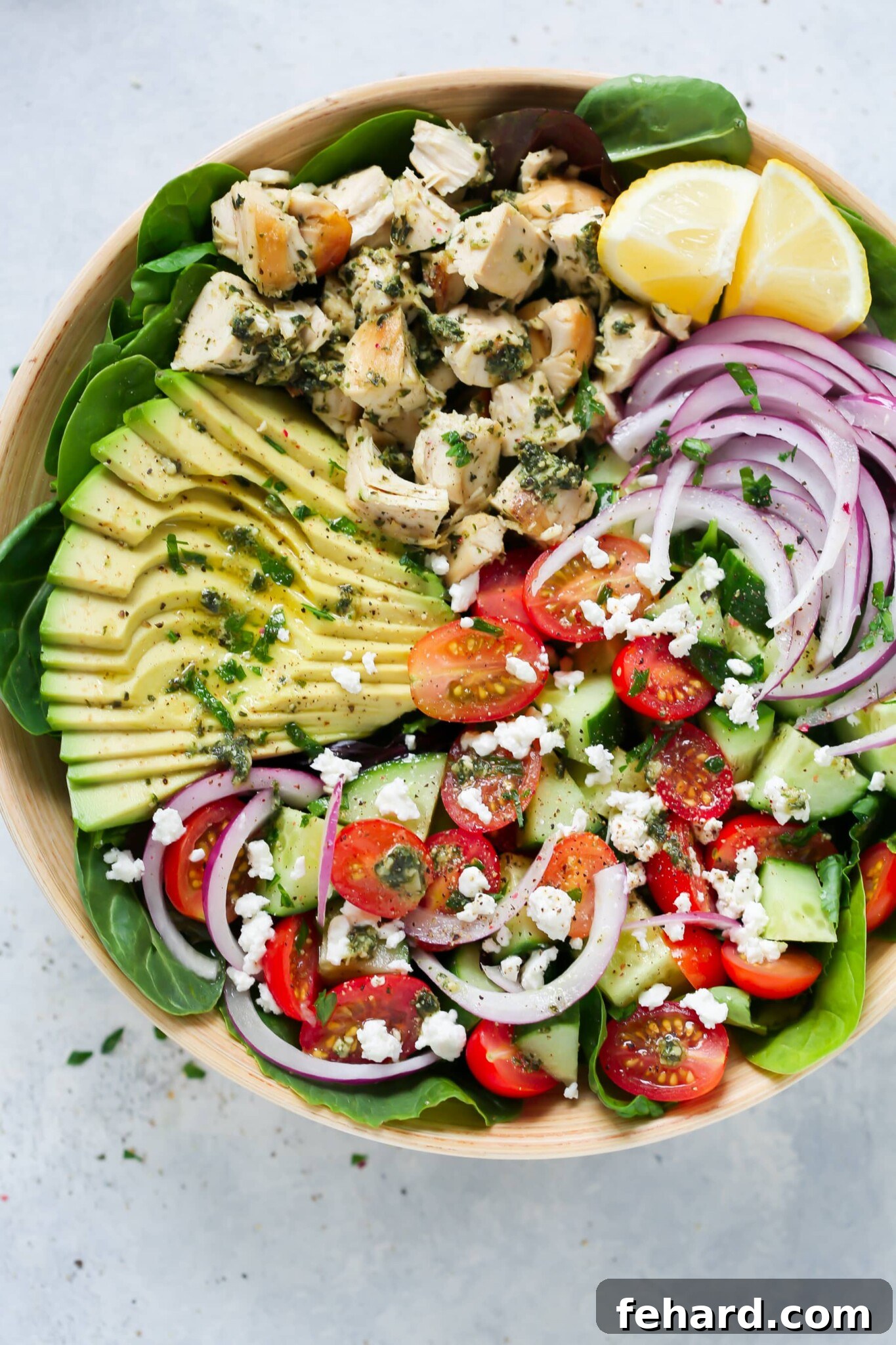 Pesto chicken salad elegantly served in a large white serving bowl, garnished with fresh herbs and cherry tomatoes.