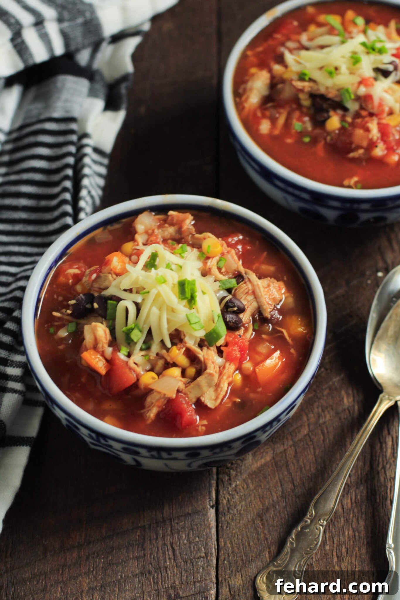 Hearty slow cooker chicken chili served in individual bowls, topped with fresh cilantro and sour cream.