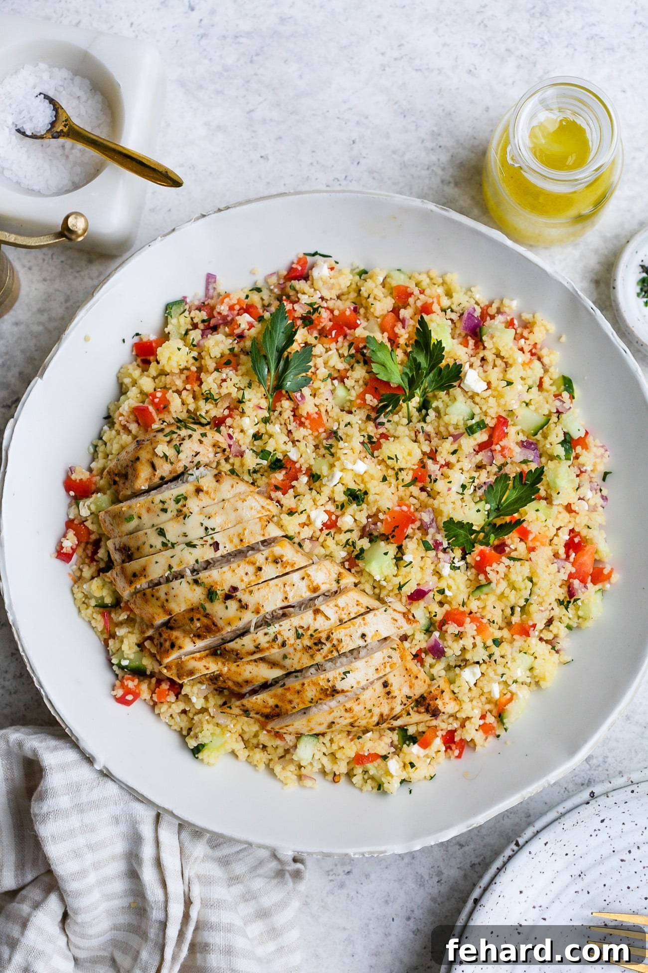 Chicken couscous salad with mango, served in a large white serving bowl, garnished with fresh cilantro.