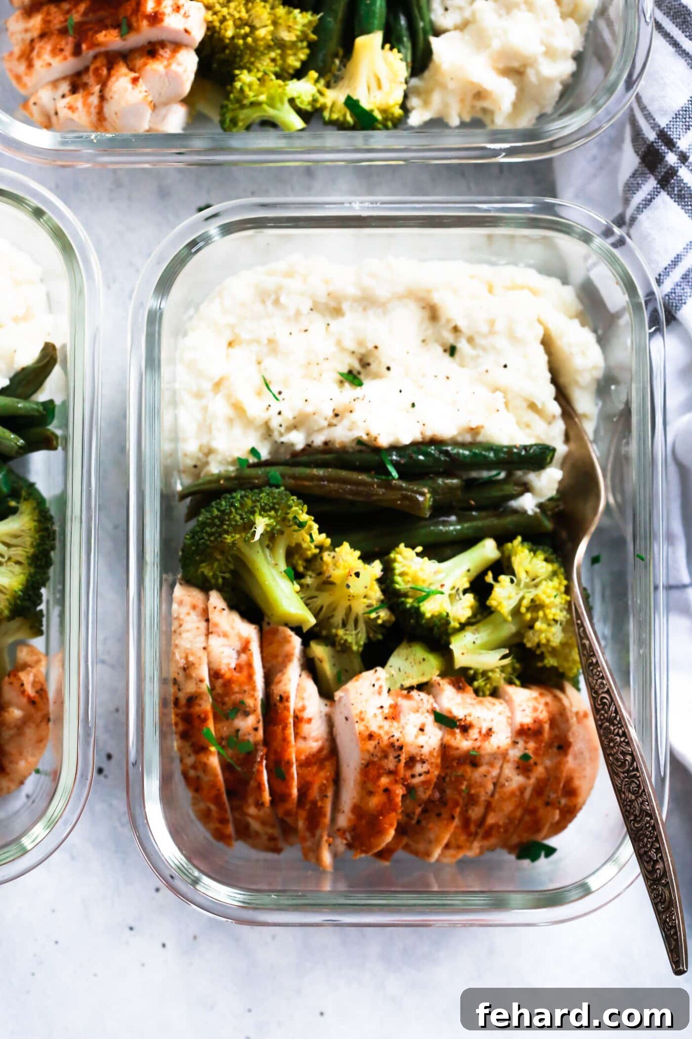 Spicy chicken meal-prep bowls arranged in glass containers, filled with chicken, rice, and vegetables, ready for the week.