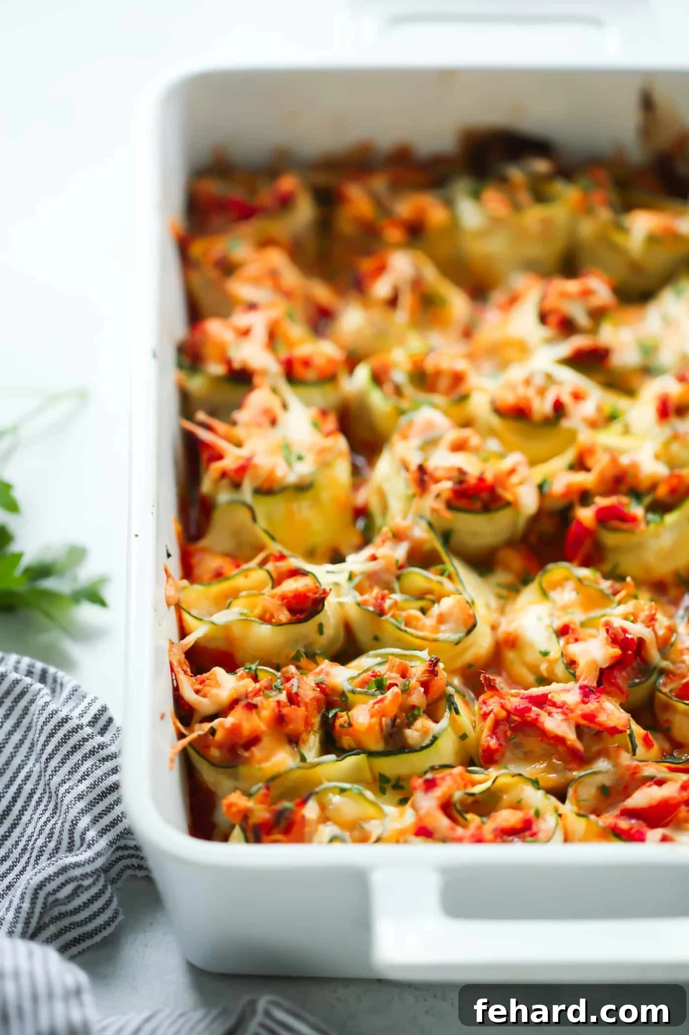 Zucchini chicken rolls baked in a white baking dish, showing off their cheesy filling and golden-brown tops.