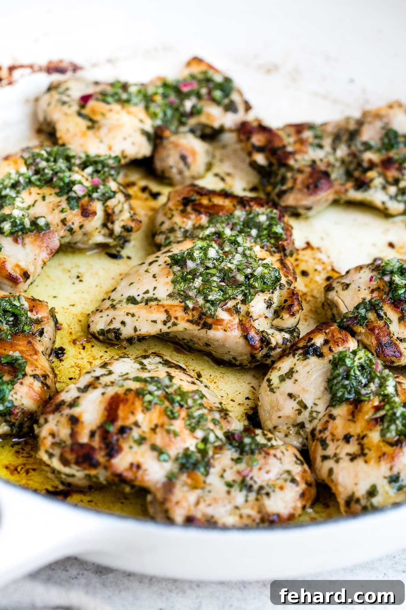 Chimichurri chicken presented in a large, white skillet, garnished with fresh parsley and cilantro.