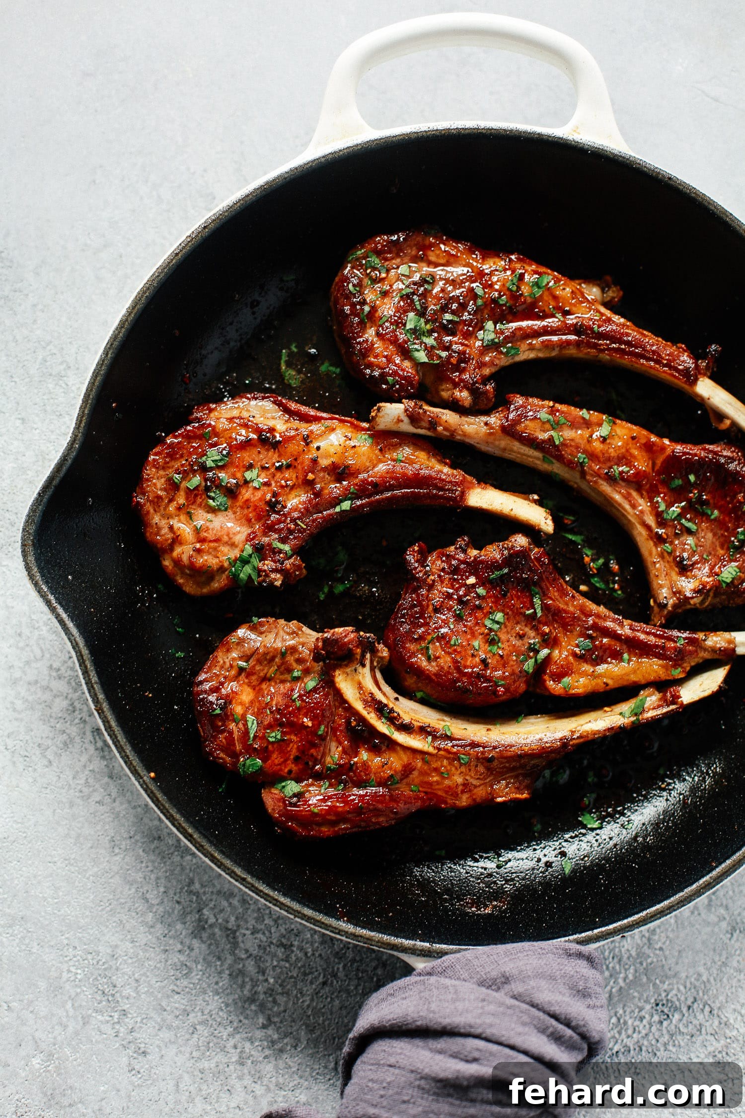 A single perfectly seared garlic butter lamb chop in a cast iron skillet, ready to be served.
