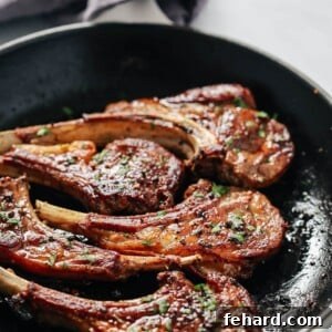 Overhead view of a skillet containing garlic butter lamb chops