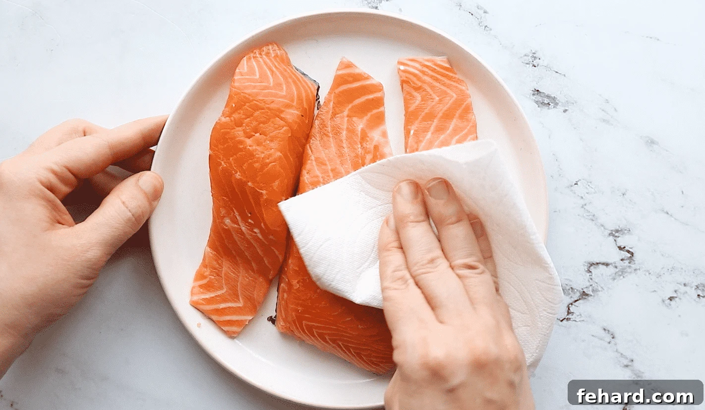 Patting salmon fillets dry with a paper towel for baking