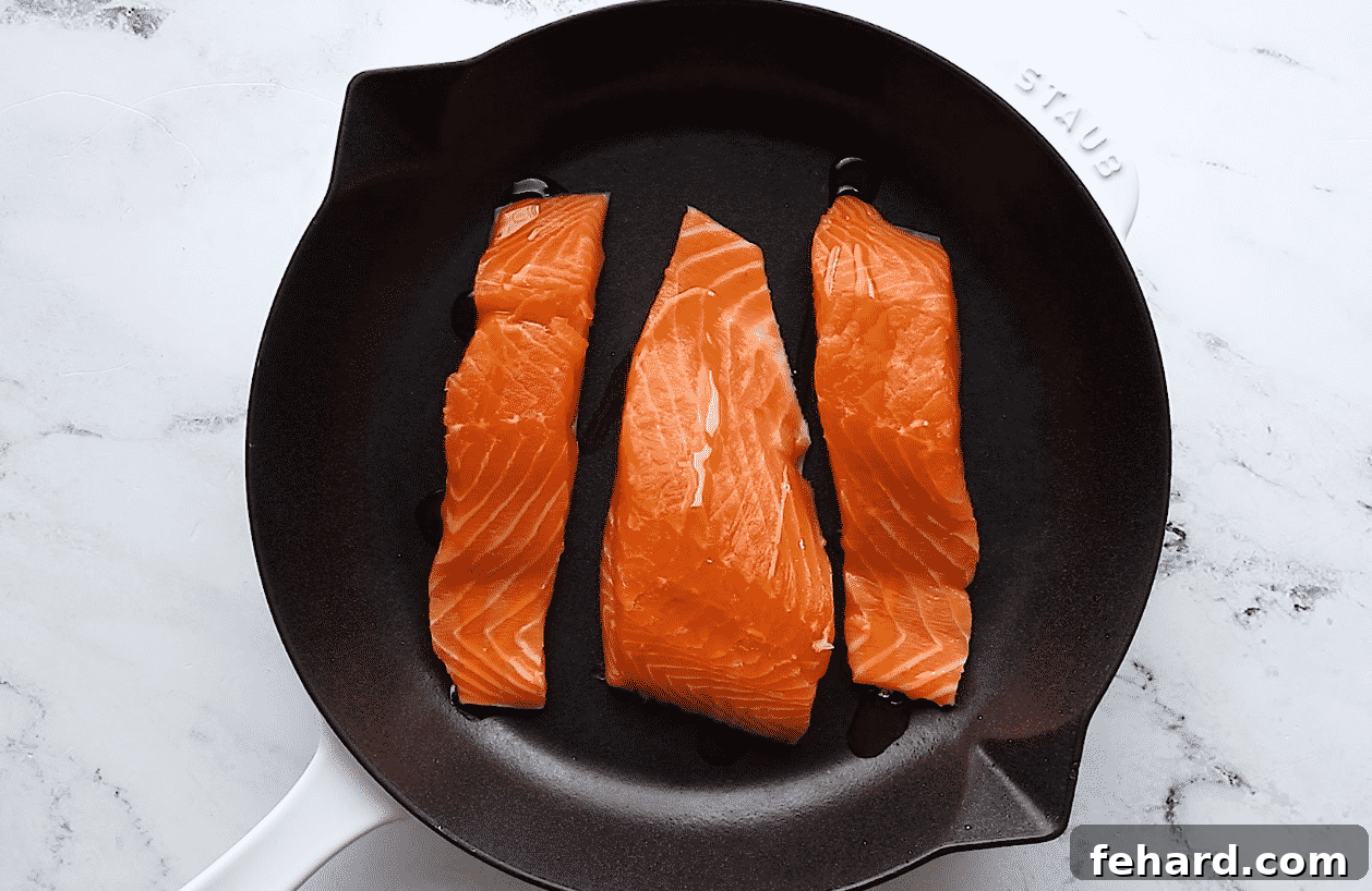 Drizzling olive oil over salmon fillets before seasoning