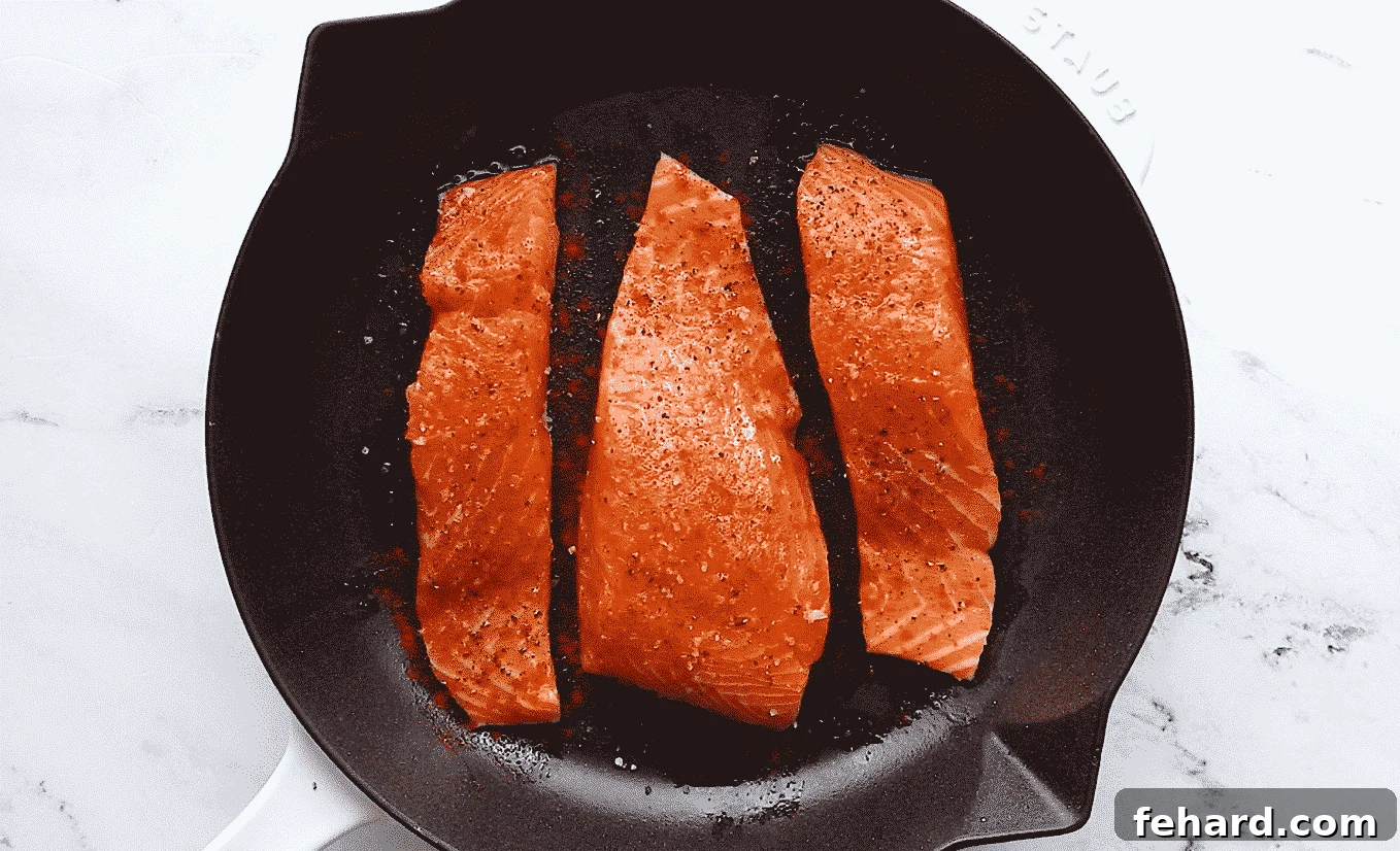 Seasoning salmon with salt, black pepper, and paprika