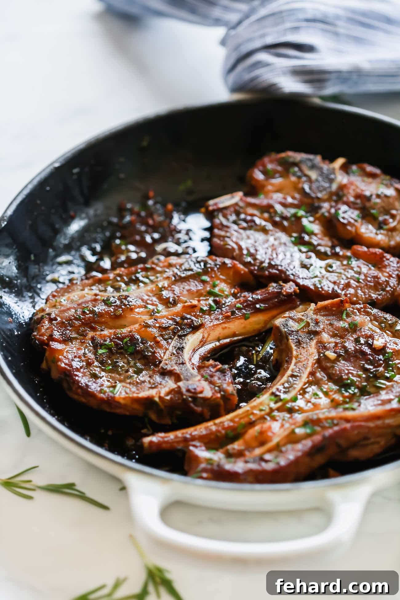 A top-down view of cooked Garlic Herb Lamb Chops resting on a cutting board, garnished with fresh rosemary and garlic.