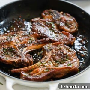 A close up of a white cast iron skillet containing Garlic Herb Lamb Chops