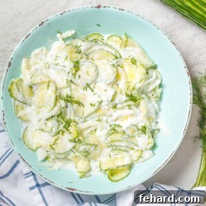 Cucumber and Onion Salad in a blue bowl, garnished with fresh dill.
