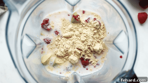 Close-up of a blender jar containing vibrant raspberry smoothie ingredients ready for blending.