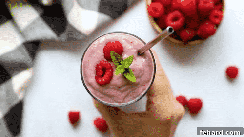 Close-up of a tall glass containing a perfectly blended raspberry smoothie, ready to be enjoyed.