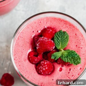 Overhead view of a low-carb raspberry smoothie garnished with fresh berries and mint