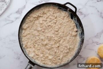 Rich Country Sausage Gravy 8 Thickened sausage gravy in skillet with biscuits next to skillet.