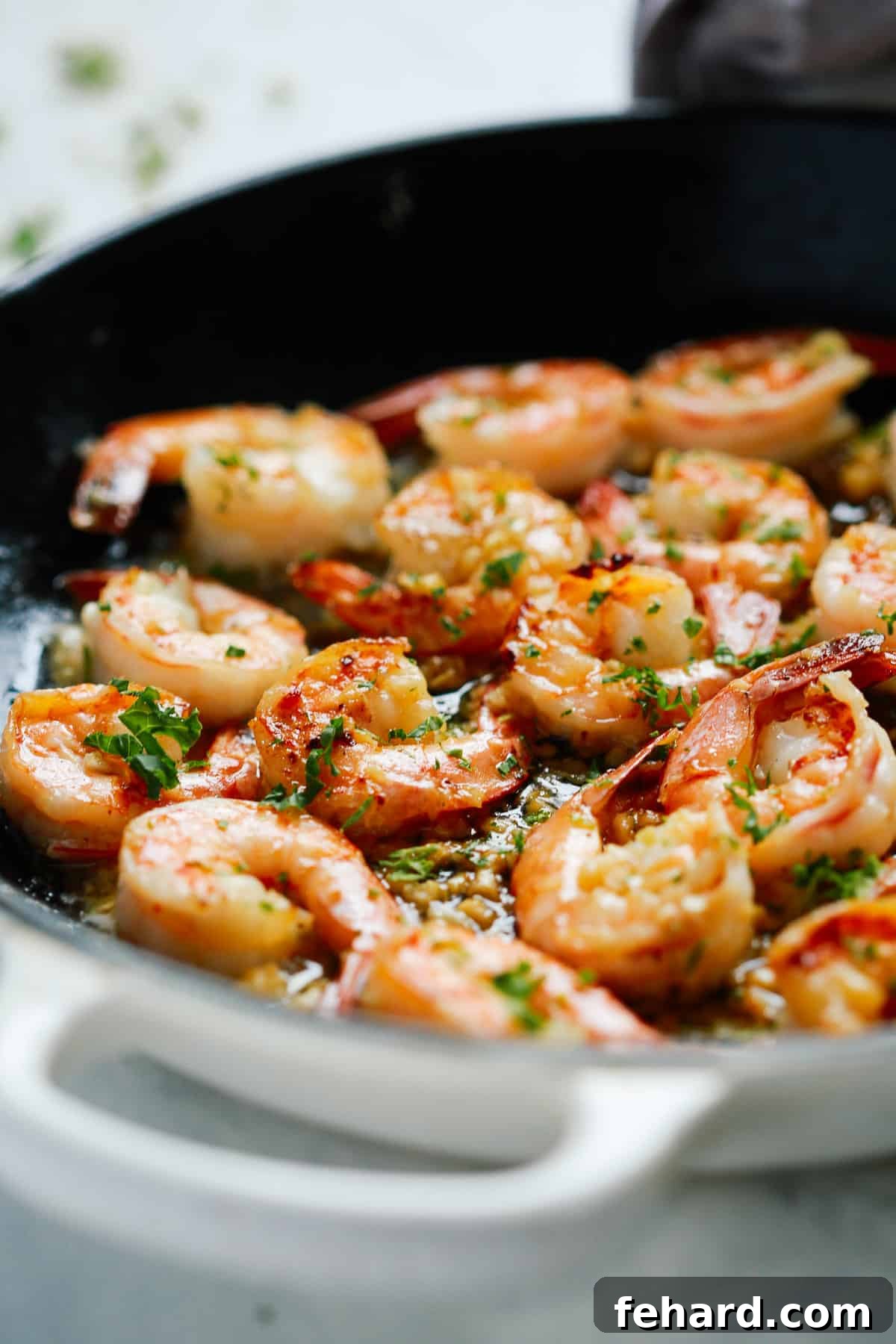 Shrimp being actively cooked in a skillet, tossing in the butter and garlic sauce.