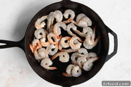 Raw shrimp in a cast iron skillet, seasoned and ready to cook.