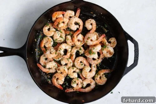 Garlic butter shrimp tossed in the skillet, fully cooked and coated in sauce.