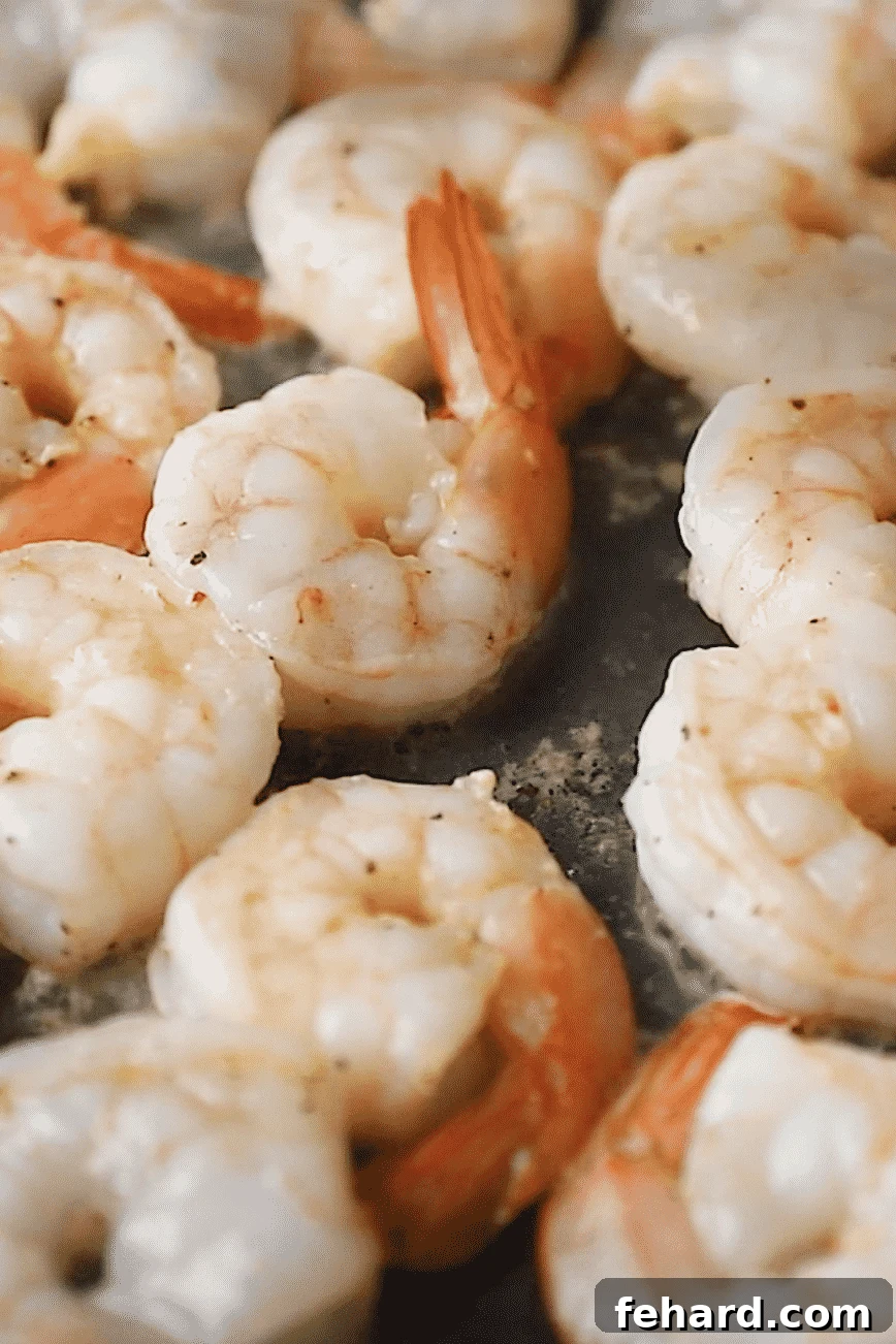 Close-up of shrimp turning pink and opaque in the skillet, indicating they are cooked.