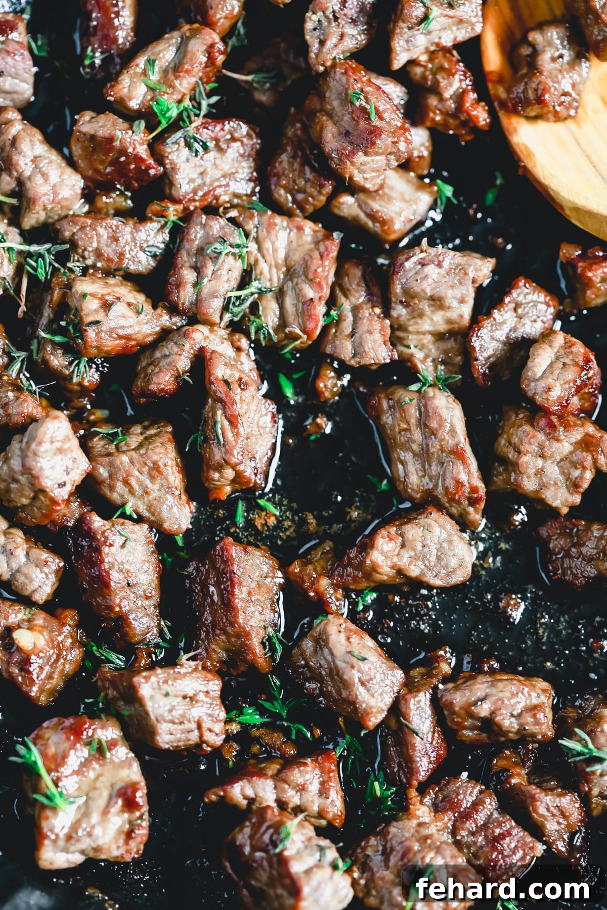 Close-up of perfectly seared sirloin steak bites glistening with garlic butter in a skillet.