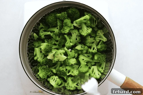 Pan with broccoli florets steaming in a basket