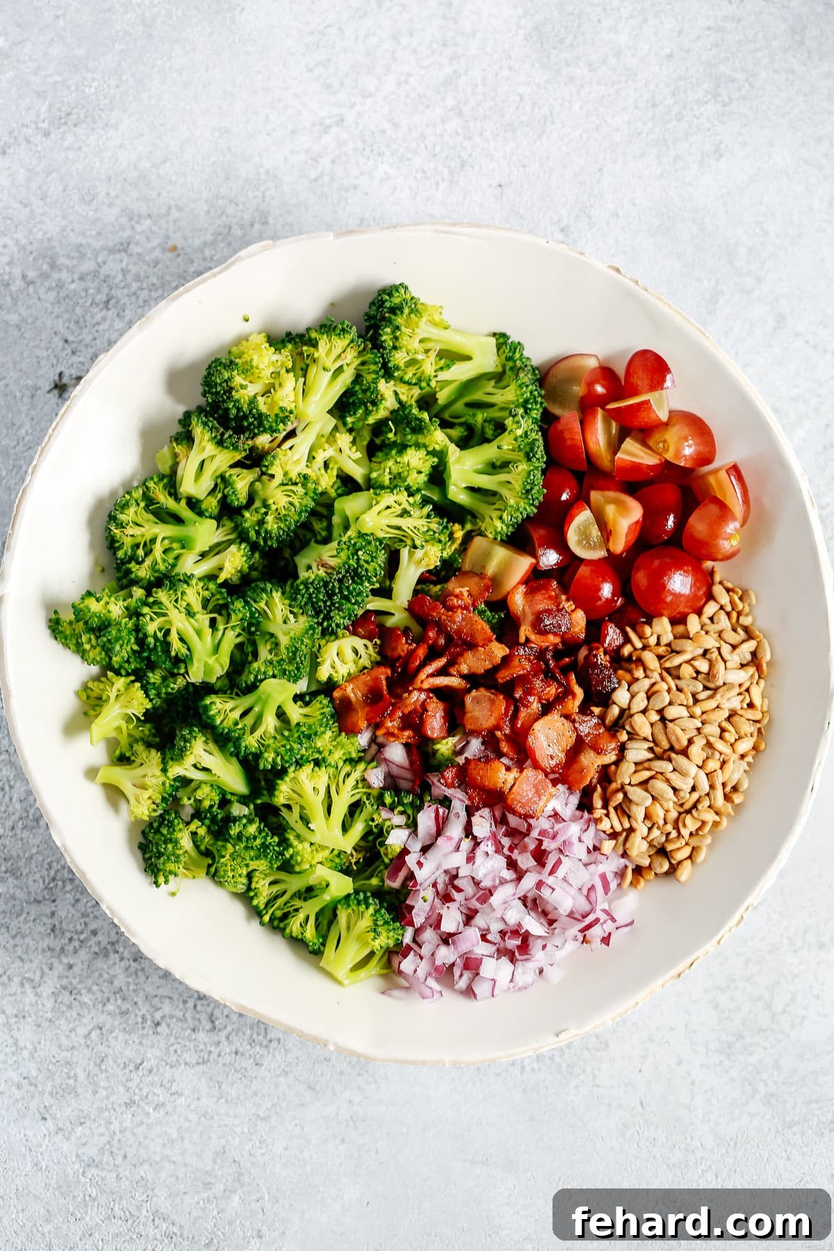 The Art of Assembling Your Perfect Broccoli Salad Broccoli salad ingredients separated into clusters in a bowl, before mixing