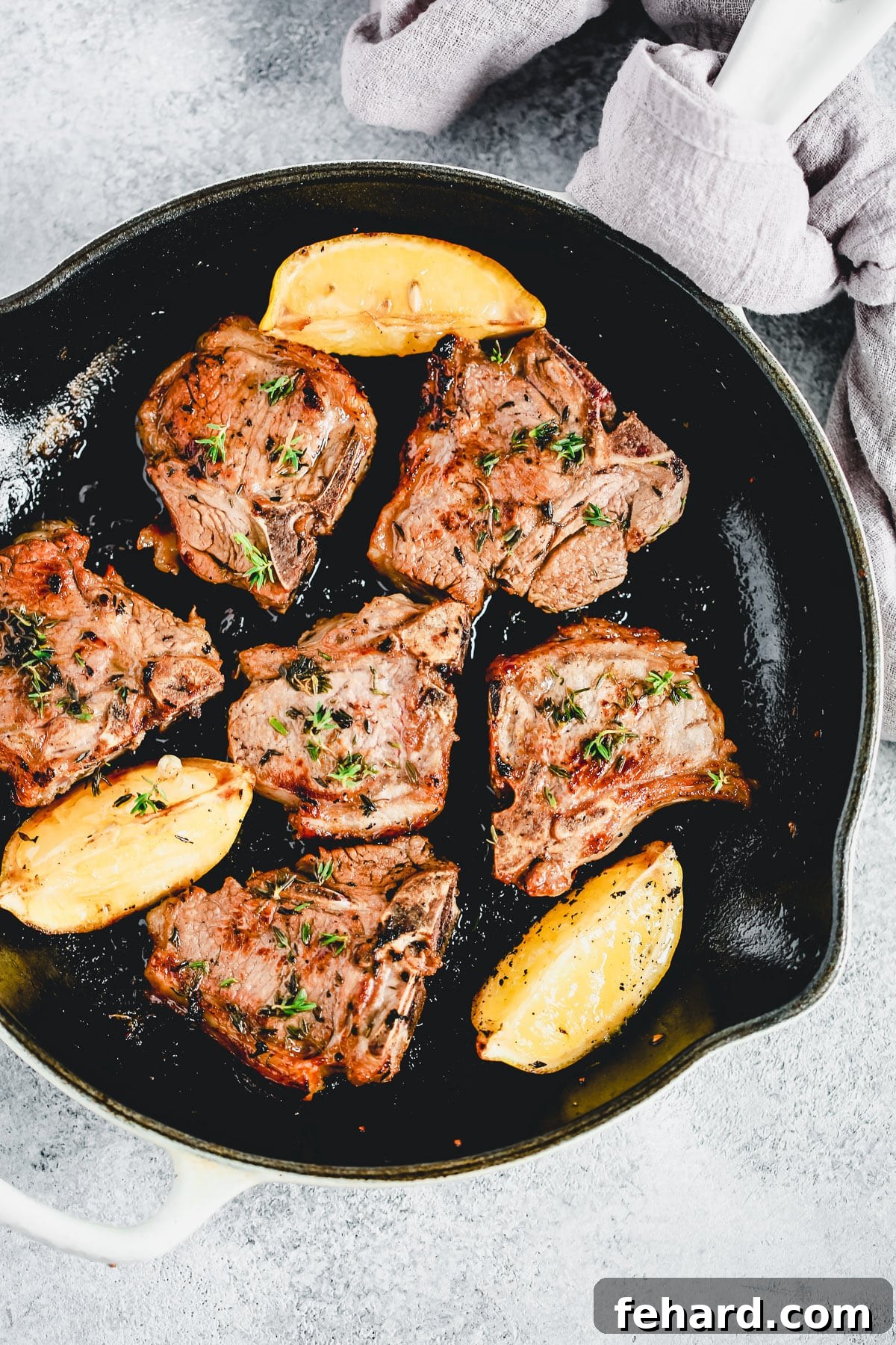 Lemon Thyme Lamb Chops sizzling in a cast iron skillet, ready to be flipped