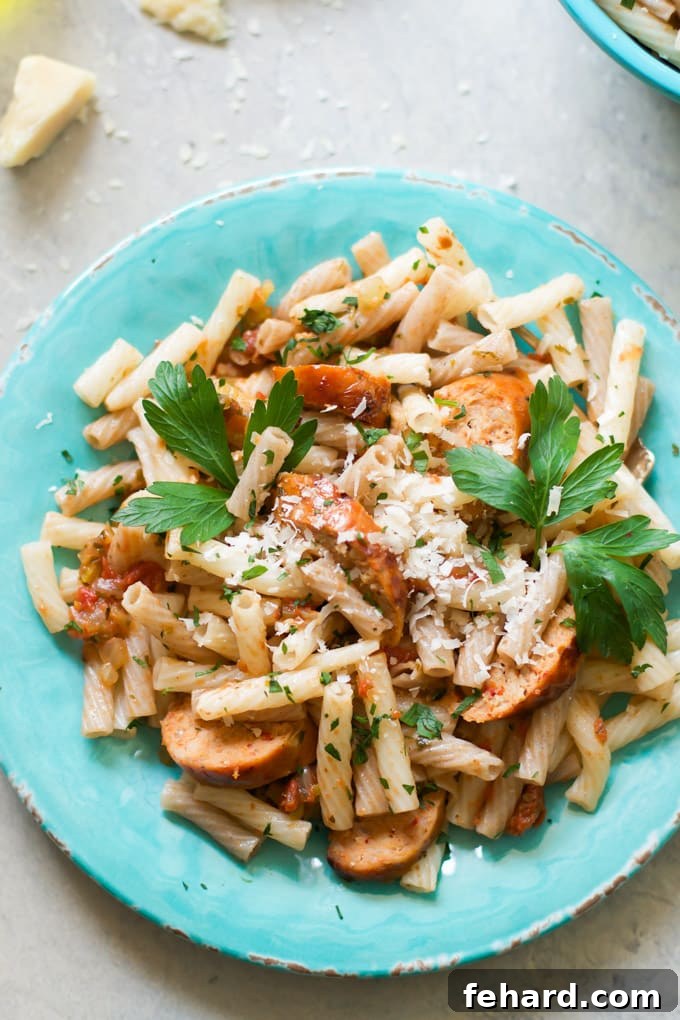 Sausage Quinoa Pasta Ready to Serve Finished Sausage Quinoa Pasta topped with grated cheese and fresh parsley in a white bowl