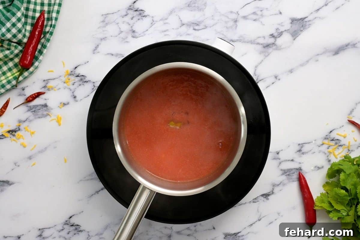 Homemade Buffalo Sauce for Pizza A saucepan on a stovetop, containing freshly made buffalo sauce after honey has been stirred in, showing its rich, glossy texture.