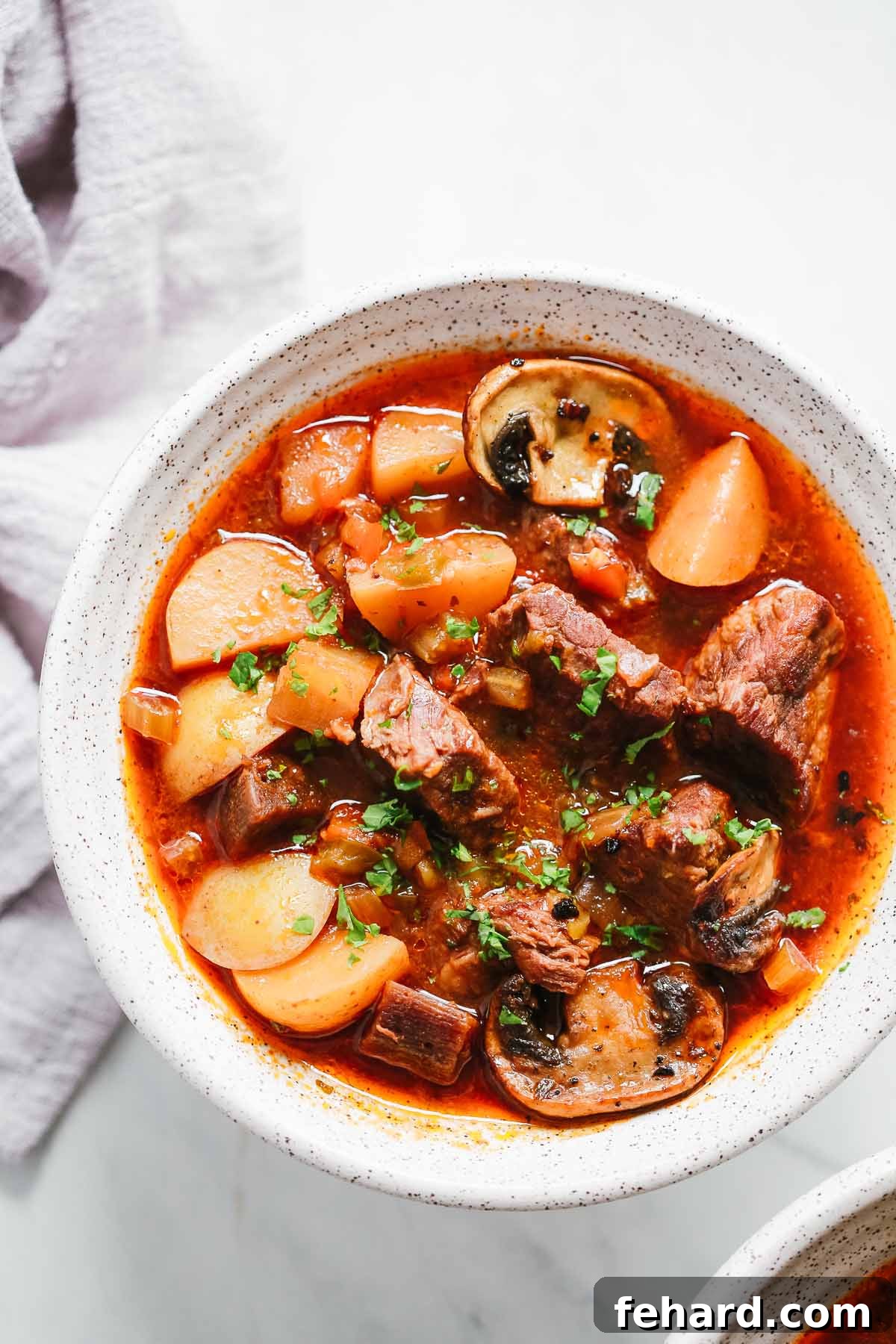 closeup of a white bowl containing Instant Pot Beef Stew