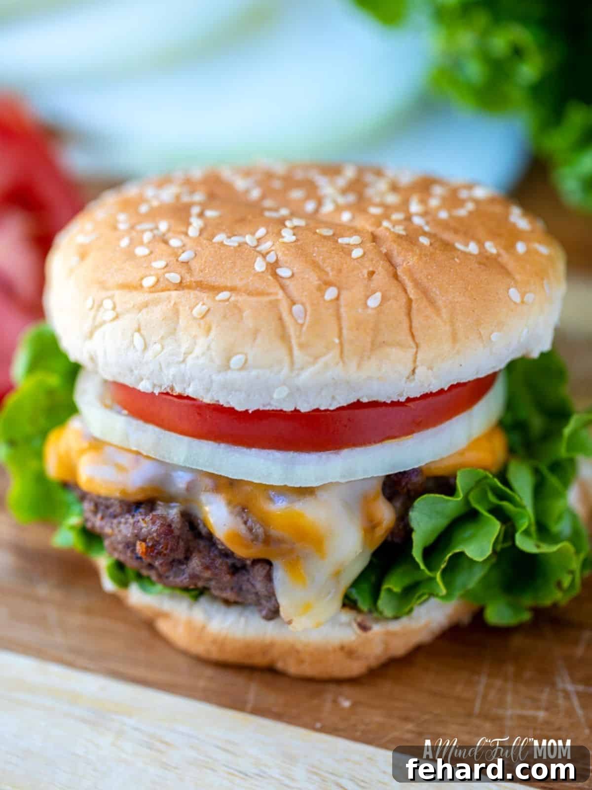 A perfectly cooked, juicy hamburger on a cutting board, ready to be served with fresh lettuce and ripe tomatoes.