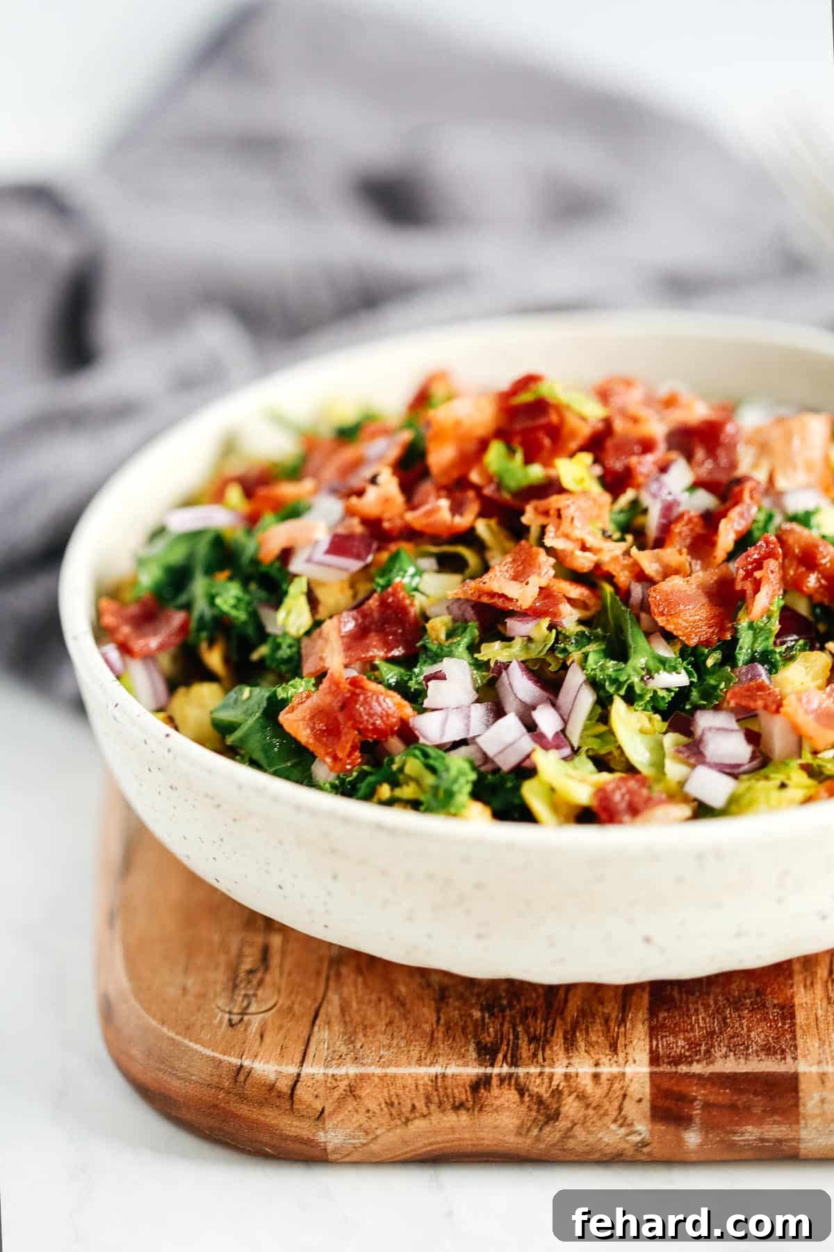 A close-up of thinly sliced Brussels sprouts and crispy bacon, ready for mixing in the salad.